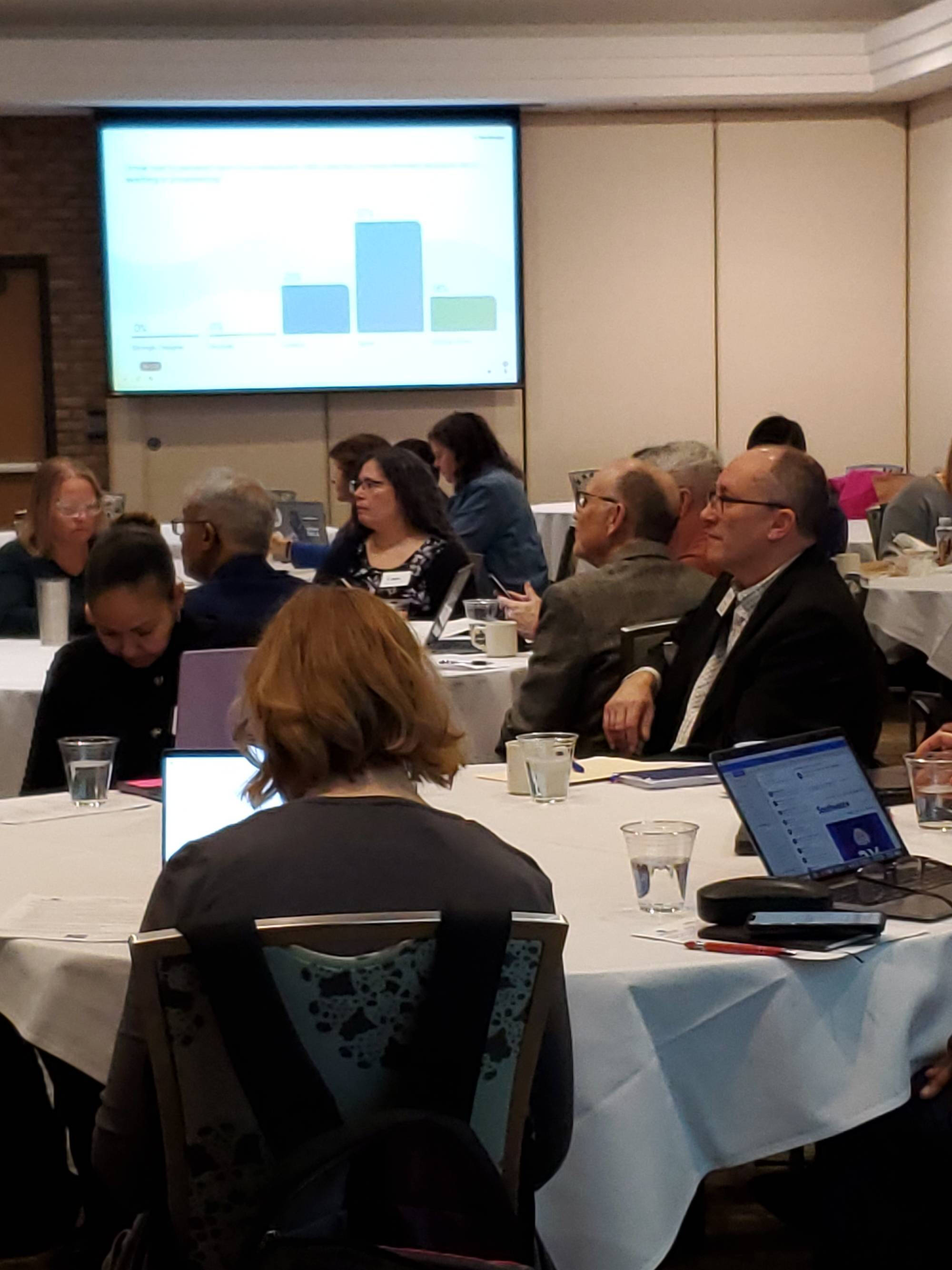 Attendees seated around a table at the GVSU Assessment Conference 2025, listening to keynote